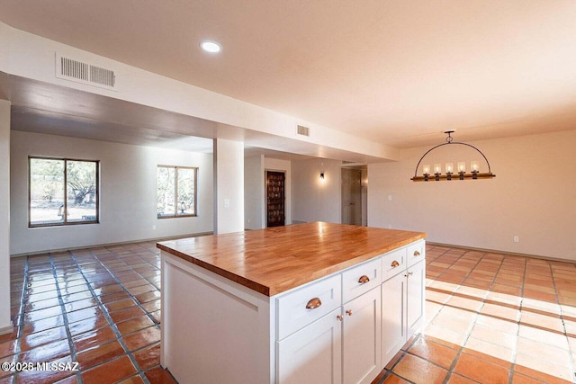 kitchen featuring a center island, decorative light fixtures, white cabinetry, a notable chandelier, and butcher block countertops