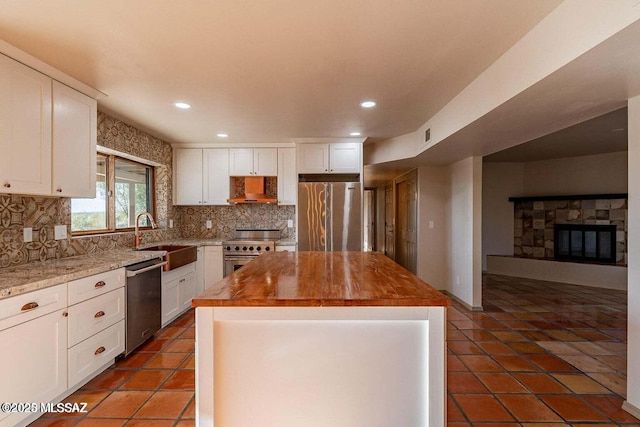 kitchen with white cabinetry, stainless steel appliances, a center island, and sink