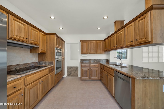 kitchen with sink, light tile patterned floors, dark stone counters, and appliances with stainless steel finishes