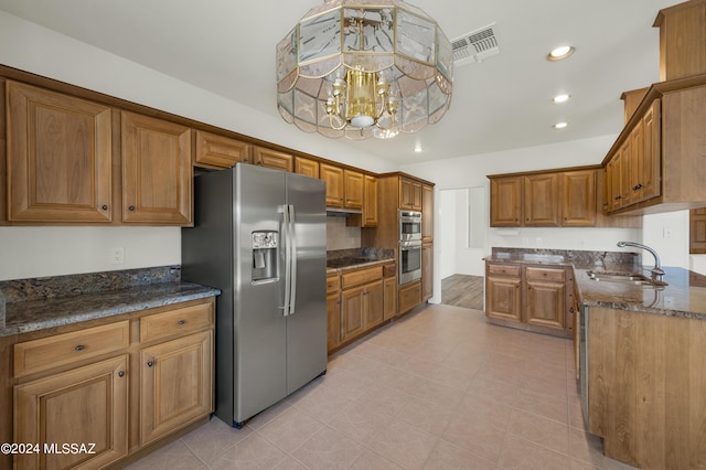 kitchen featuring dark stone counters, sink, light tile patterned floors, stainless steel appliances, and a chandelier