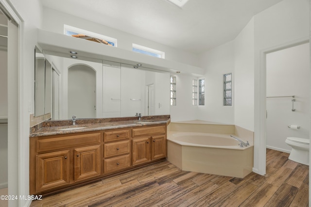 bathroom featuring a tub to relax in, vanity, and toilet