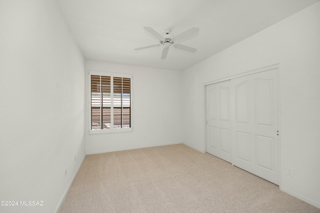 unfurnished bedroom featuring ceiling fan, light colored carpet, and a closet