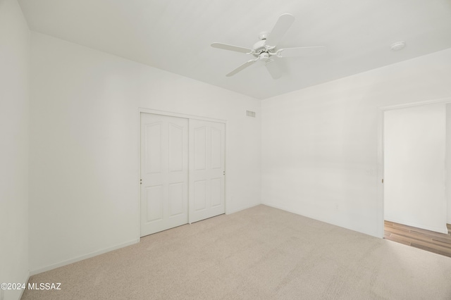 unfurnished bedroom featuring light carpet, a closet, and ceiling fan