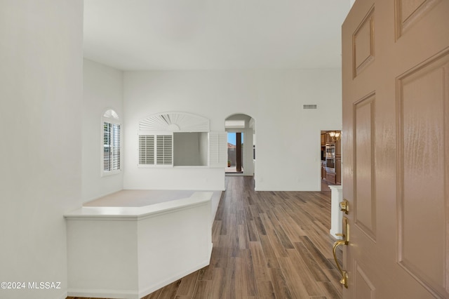 hall with a towering ceiling and hardwood / wood-style flooring