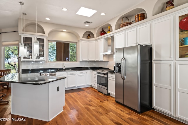 kitchen featuring white cabinets, pendant lighting, wall chimney range hood, and appliances with stainless steel finishes