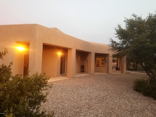 back house at dusk featuring a patio area