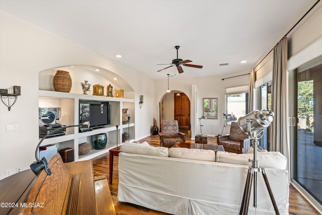 living room featuring hardwood / wood-style flooring, built in features, and ceiling fan