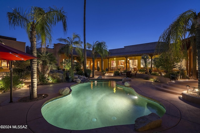 pool at dusk featuring a patio area