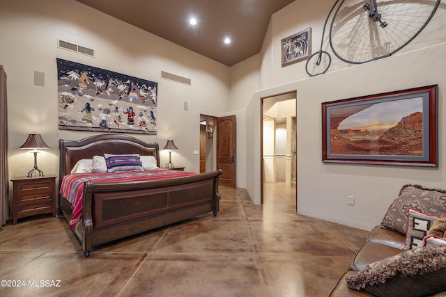 bedroom featuring concrete flooring and a high ceiling