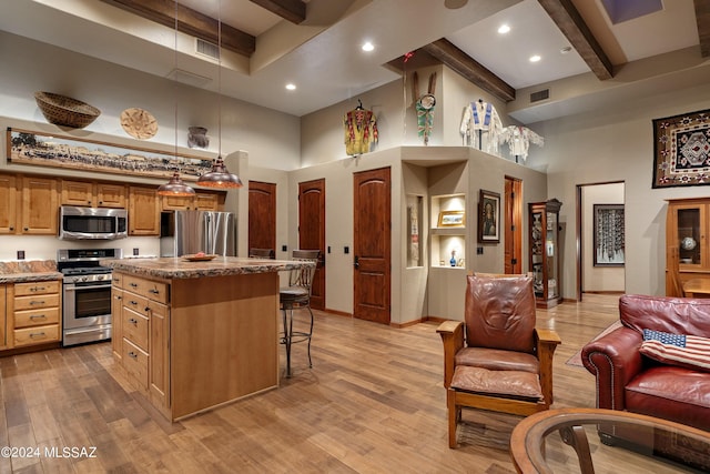 kitchen featuring a kitchen island, beamed ceiling, a high ceiling, a breakfast bar area, and stainless steel appliances