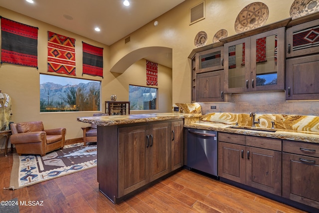 kitchen with sink, stainless steel dishwasher, kitchen peninsula, and dark brown cabinets