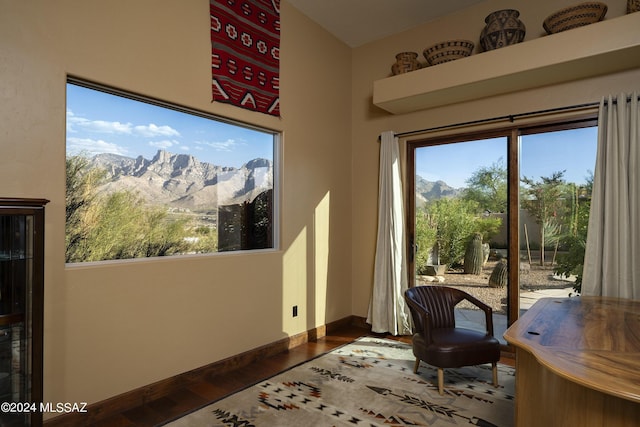 interior space with a high ceiling, dark wood-type flooring, a wealth of natural light, and a mountain view