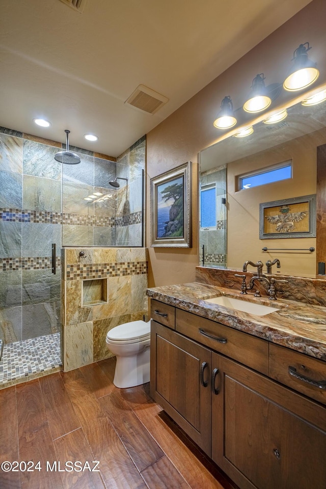 bathroom with toilet, a shower with shower door, and vanity