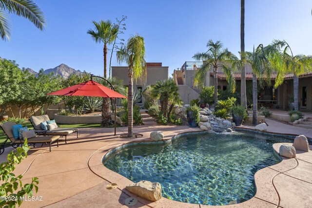 view of swimming pool featuring pool water feature, a mountain view, and a patio