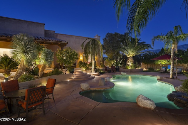 pool at twilight with a patio area