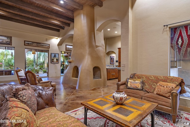 living room with beamed ceiling, a high ceiling, and wooden ceiling