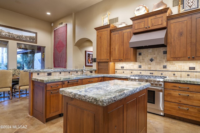 kitchen with a center island, decorative backsplash, kitchen peninsula, high end stove, and range hood