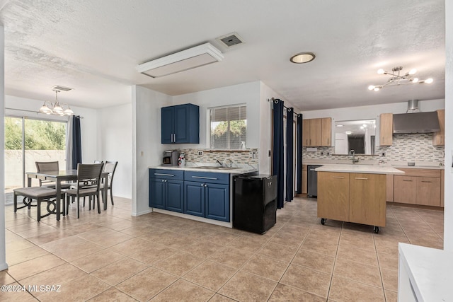 kitchen with blue cabinetry, a kitchen island, light tile patterned floors, and a notable chandelier