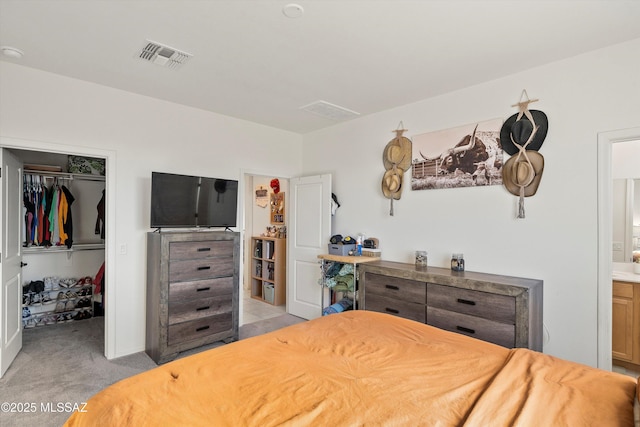 bedroom with visible vents, connected bathroom, a walk in closet, a closet, and light colored carpet