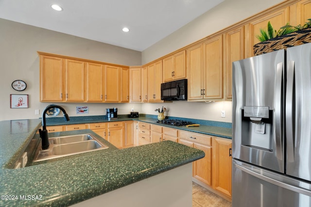 kitchen with light brown cabinetry, stainless steel fridge, sink, and gas stovetop