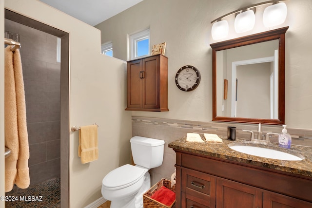 bathroom with vanity, tile walls, and toilet