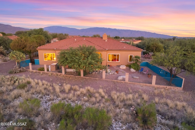 back house at dusk featuring a mountain view and a patio