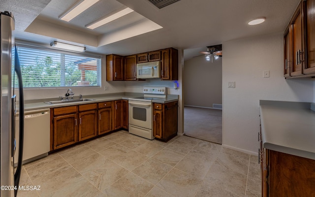 kitchen featuring ceiling fan, white appliances, sink, and a tray ceiling