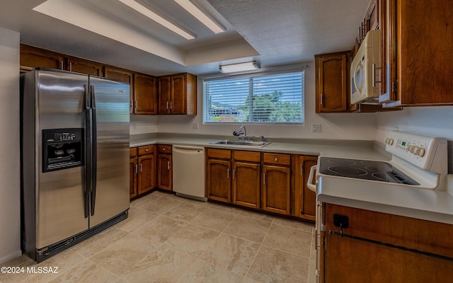 kitchen featuring white appliances, sink, and a tray ceiling