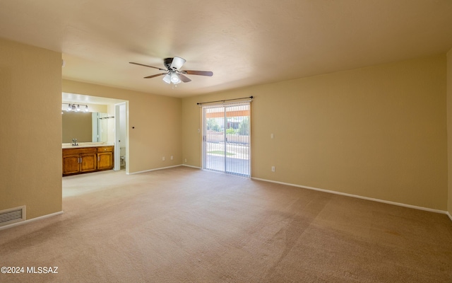 carpeted spare room featuring ceiling fan and sink