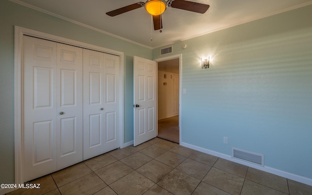 unfurnished bedroom featuring ceiling fan, a closet, light tile patterned flooring, and crown molding