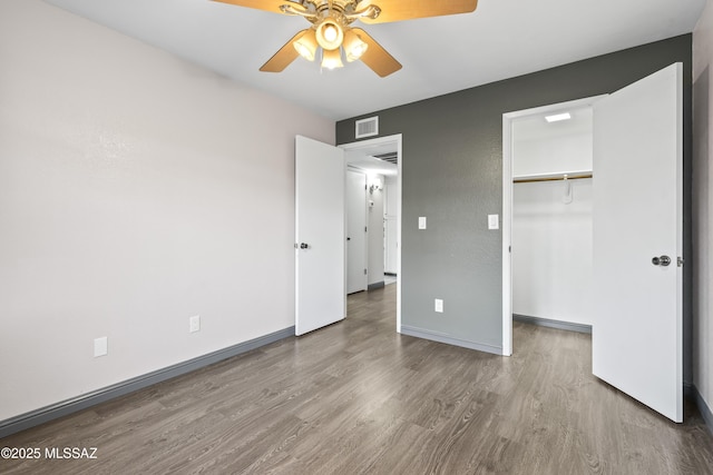 unfurnished bedroom featuring hardwood / wood-style floors, a closet, and ceiling fan