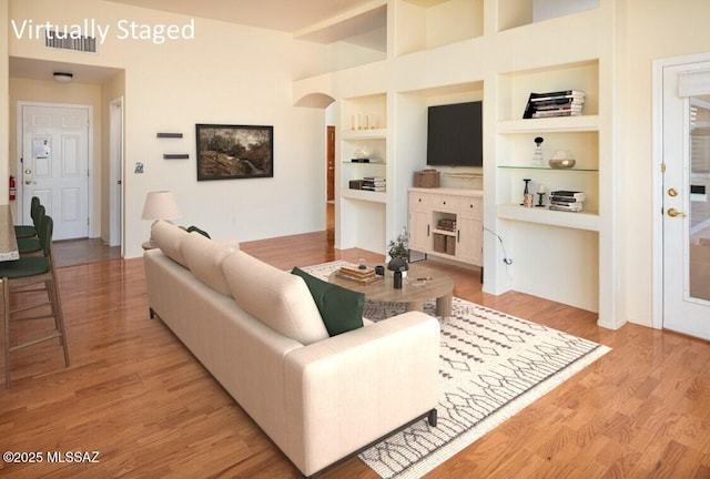 living area with visible vents, built in features, light wood finished floors, and a fireplace