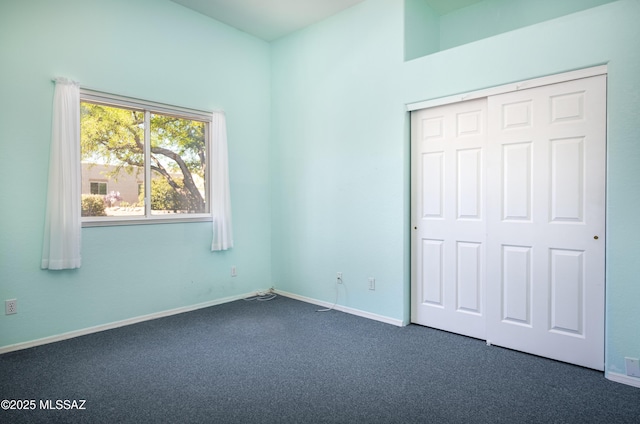 unfurnished bedroom with baseboards, a closet, and dark colored carpet