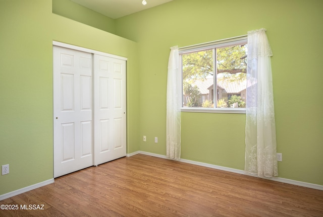 unfurnished bedroom featuring a closet, baseboards, and wood finished floors