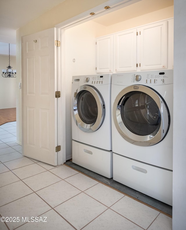 laundry room with light tile patterned floors, a notable chandelier, cabinet space, and washer and clothes dryer