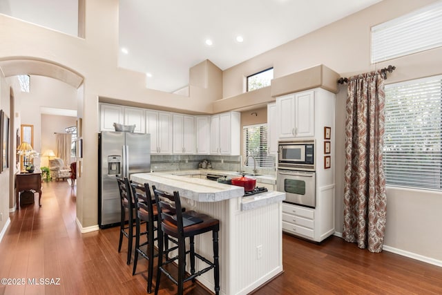 kitchen featuring backsplash, stainless steel appliances, a center island, white cabinets, and a kitchen bar