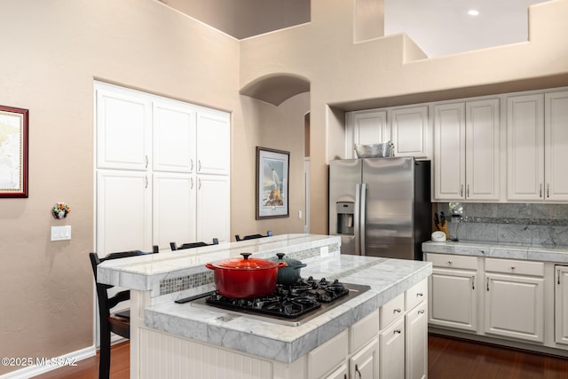 kitchen with white cabinetry, backsplash, a center island, stainless steel appliances, and dark wood-type flooring