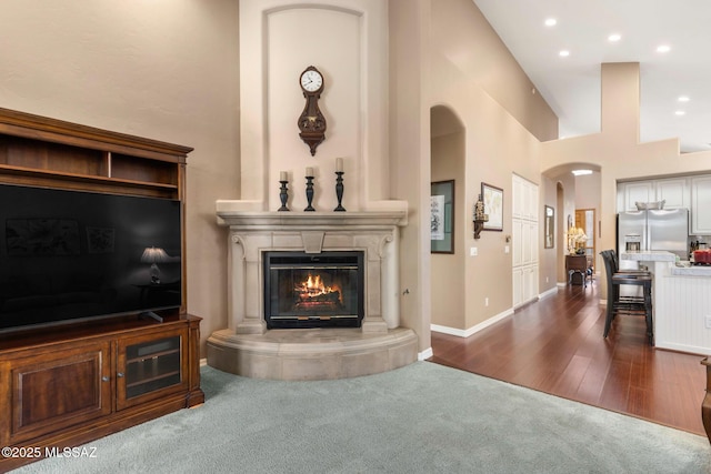 carpeted living room featuring a towering ceiling