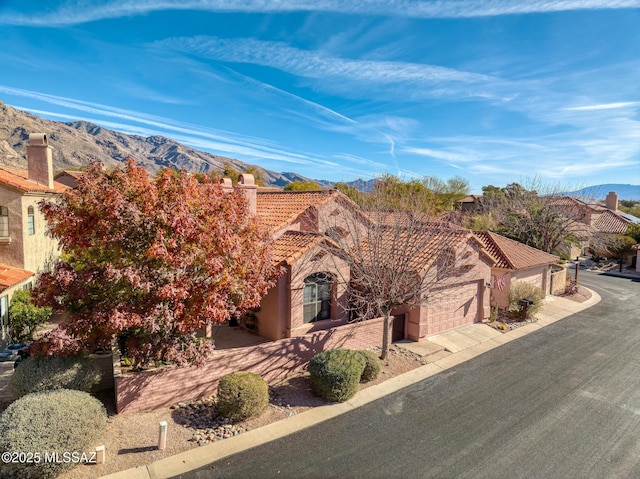 view of front of property featuring a tile roof, a mountain view, an attached garage, and stucco siding