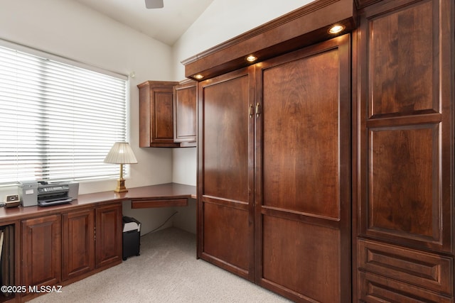 unfurnished office featuring vaulted ceiling, light colored carpet, and ceiling fan