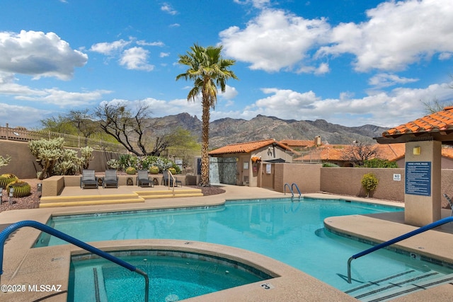 view of swimming pool with a community hot tub, a mountain view, and a patio area