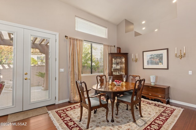 dining space featuring wood-type flooring, french doors, and a high ceiling