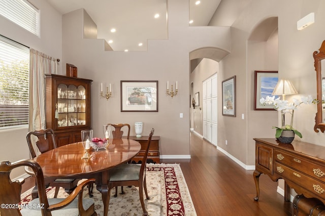 dining space featuring a towering ceiling and dark hardwood / wood-style flooring