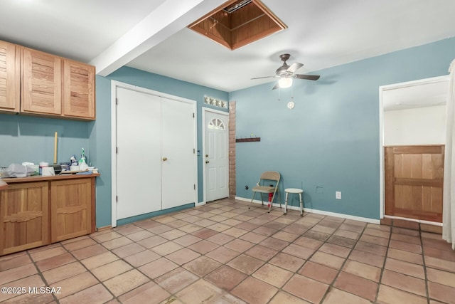 interior space featuring beamed ceiling, light brown cabinetry, and ceiling fan