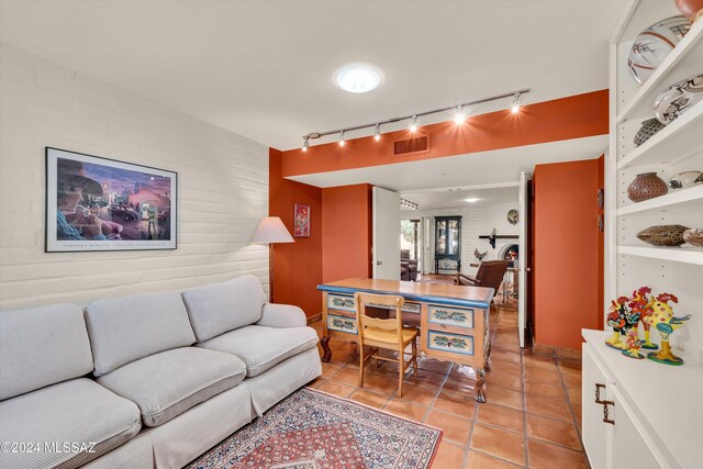 tiled living room with rail lighting and brick wall