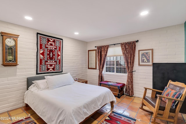 bedroom featuring tile patterned floors and brick wall