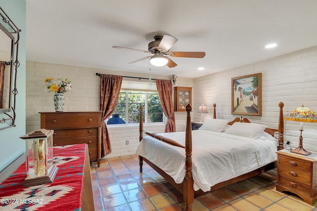 bedroom with ceiling fan, light tile patterned floors, and brick wall