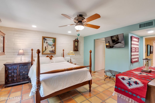 tiled bedroom with ceiling fan and brick wall