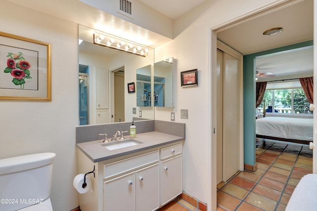 bathroom with tile patterned flooring, vanity, toilet, and ceiling fan