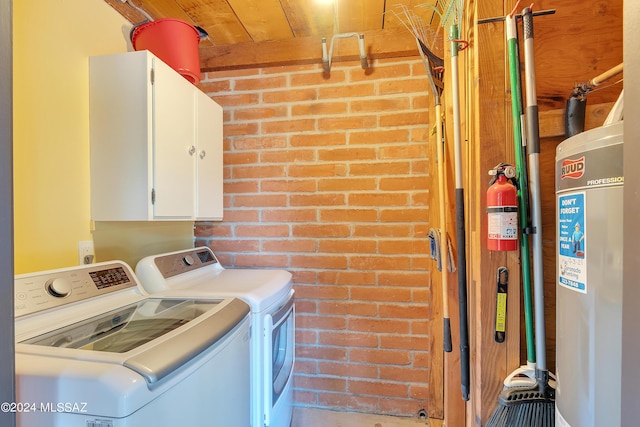 washroom with cabinets, brick wall, and washing machine and clothes dryer